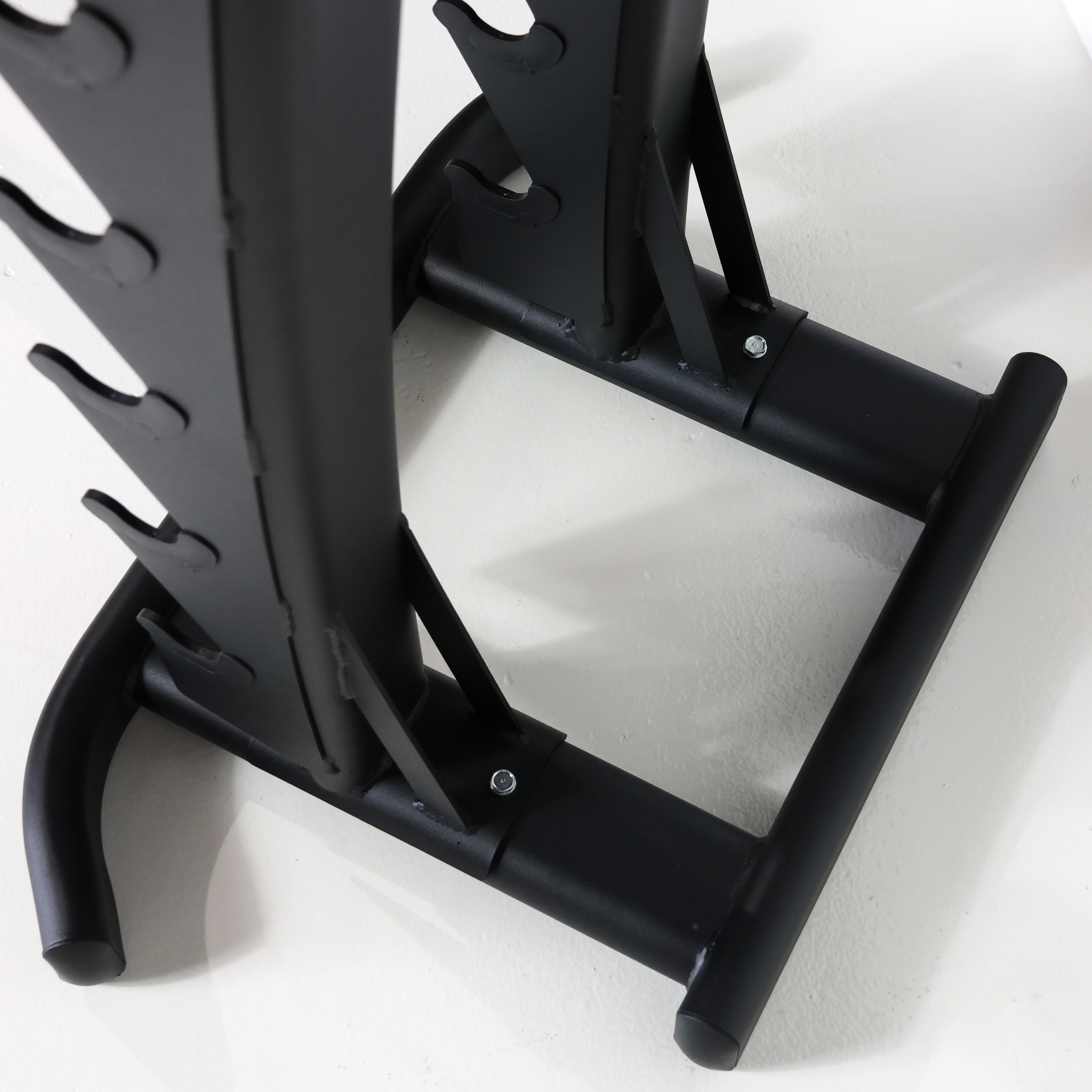 Close-up of a black metal weight bench frame showing the lower support bars and adjustment pegs on a white background.