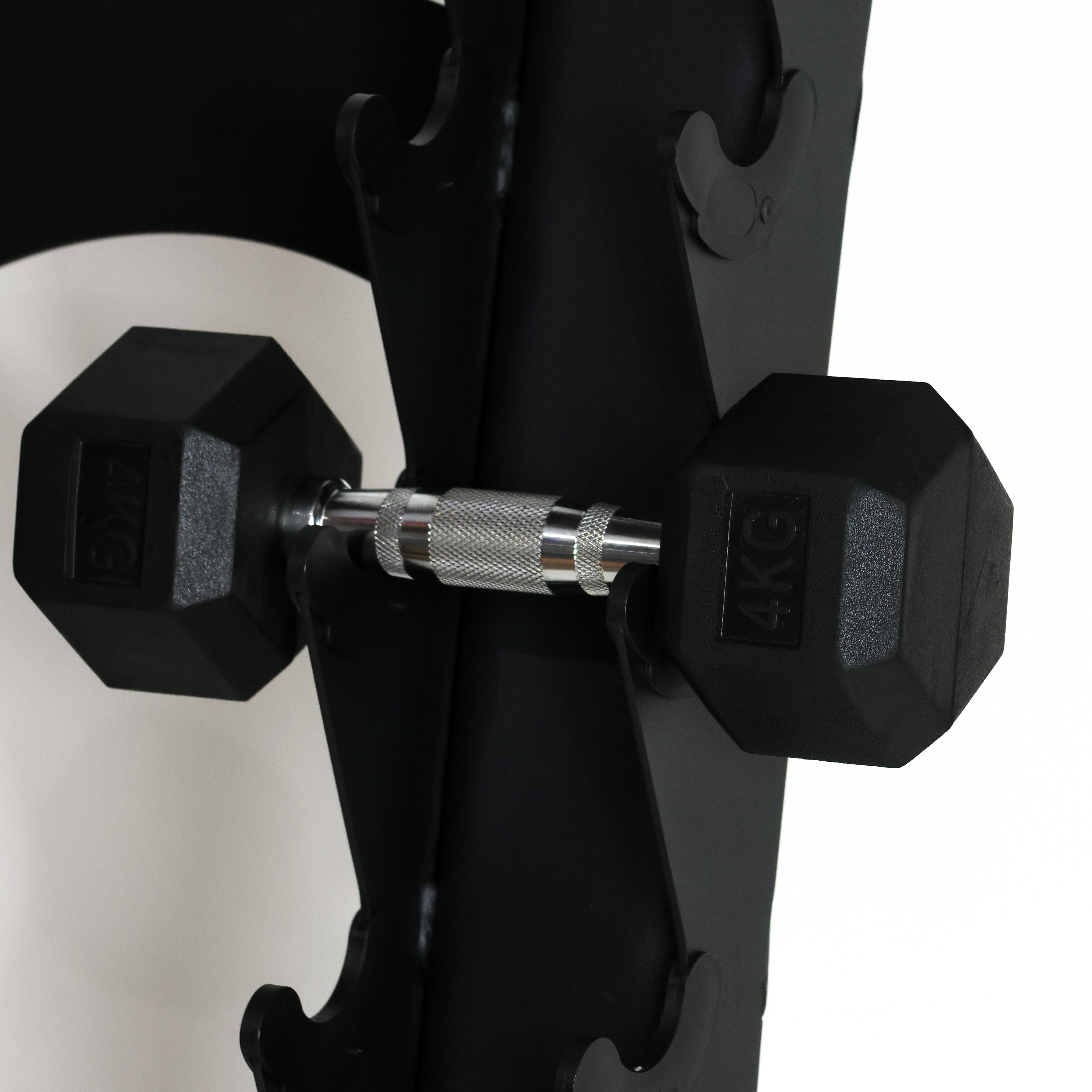 Black hex dumbbells with silver knurled handles resting on a black weight rack, with one dumbbell marked 5KG and the other marked 4KG.