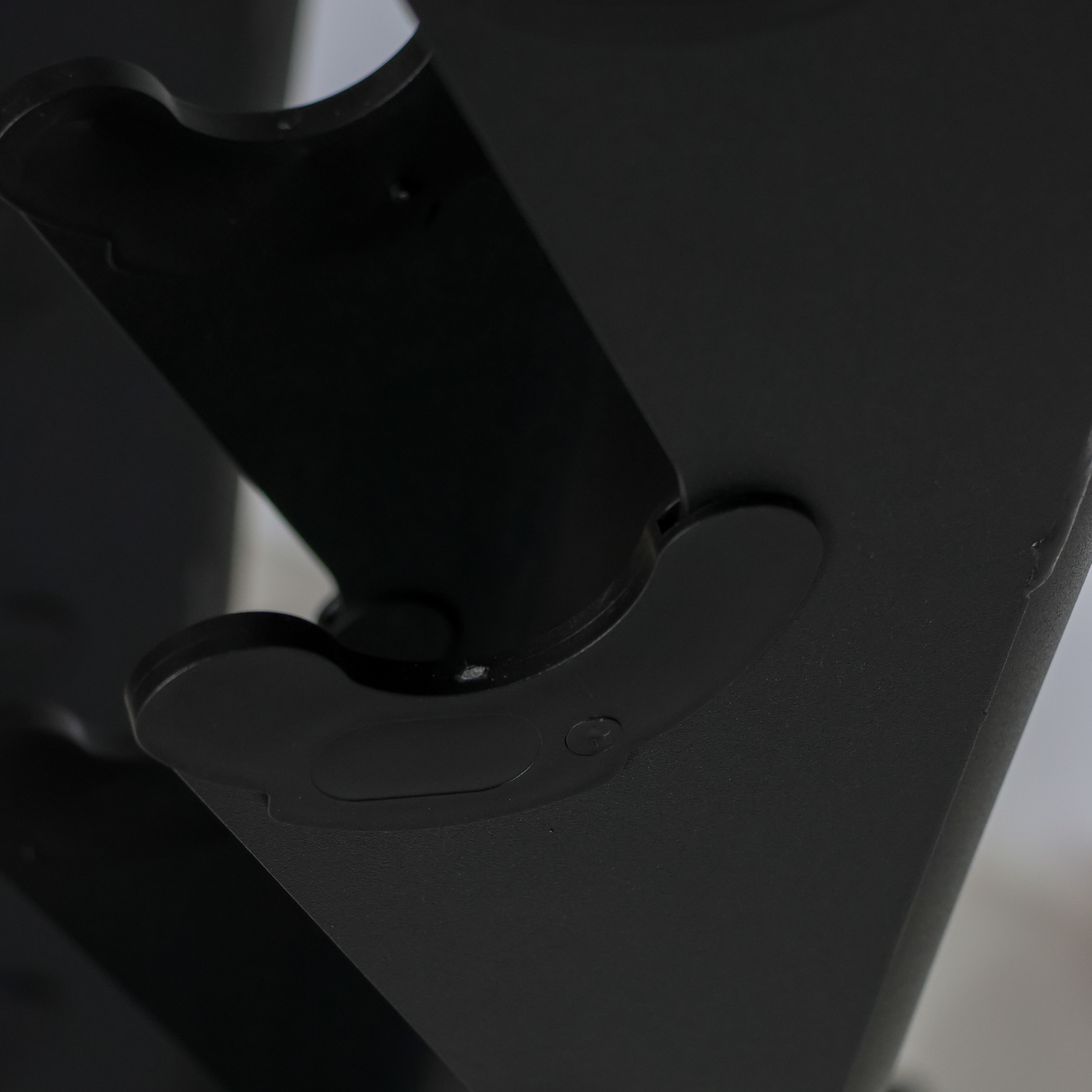Close-up detail shot of a matte black plastic component, showing a curved mounting bracket or clip with a small circular screw detail.
