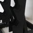 Close-up of a black metal weight rack with curved pegs holding dumbbells, set against a plain light background.