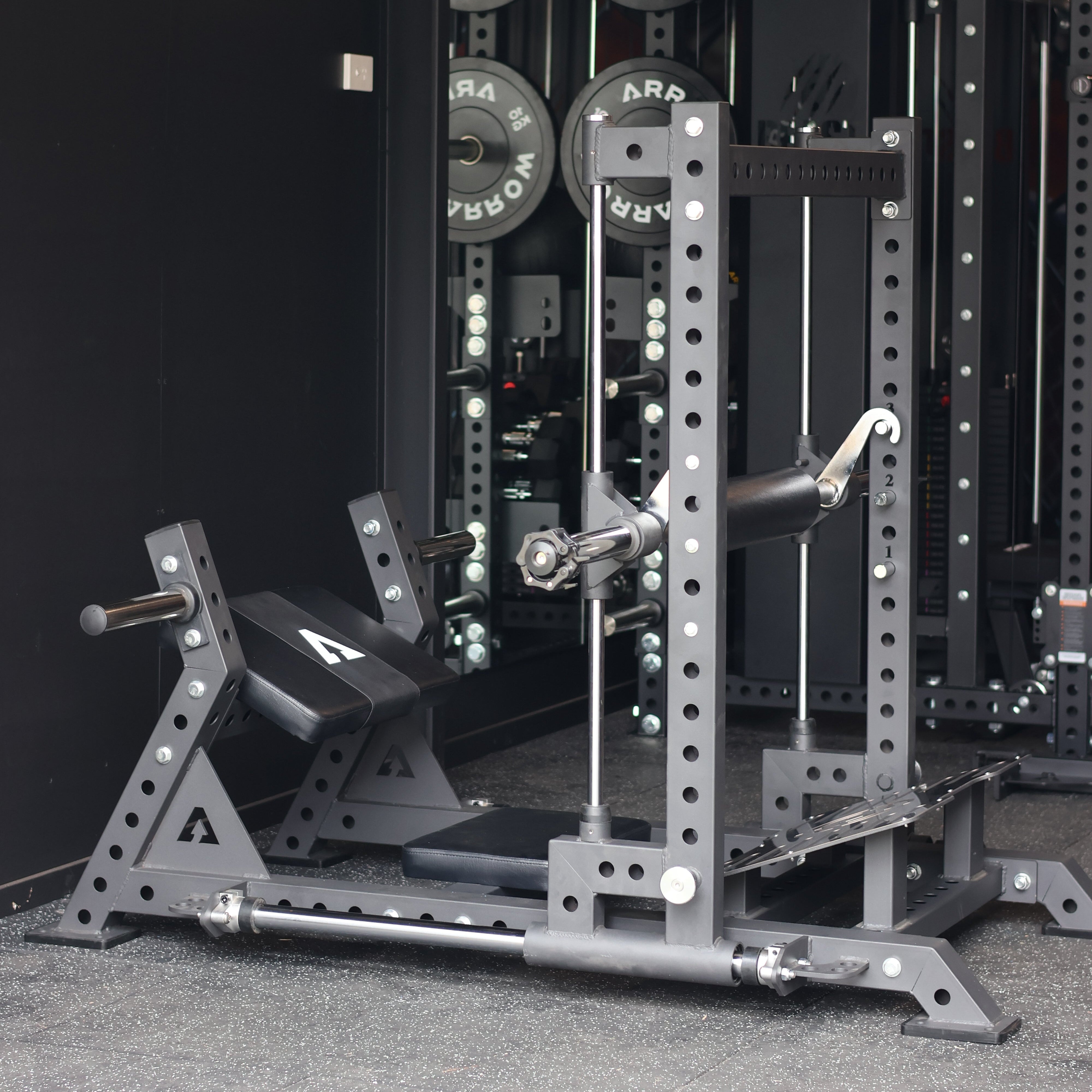 Gym equipment including weight plates and a bench press station on a dark background