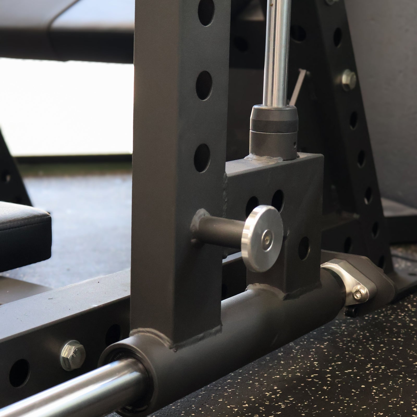 Close-up of a weightlifting bench with metal components on a speckled floor.