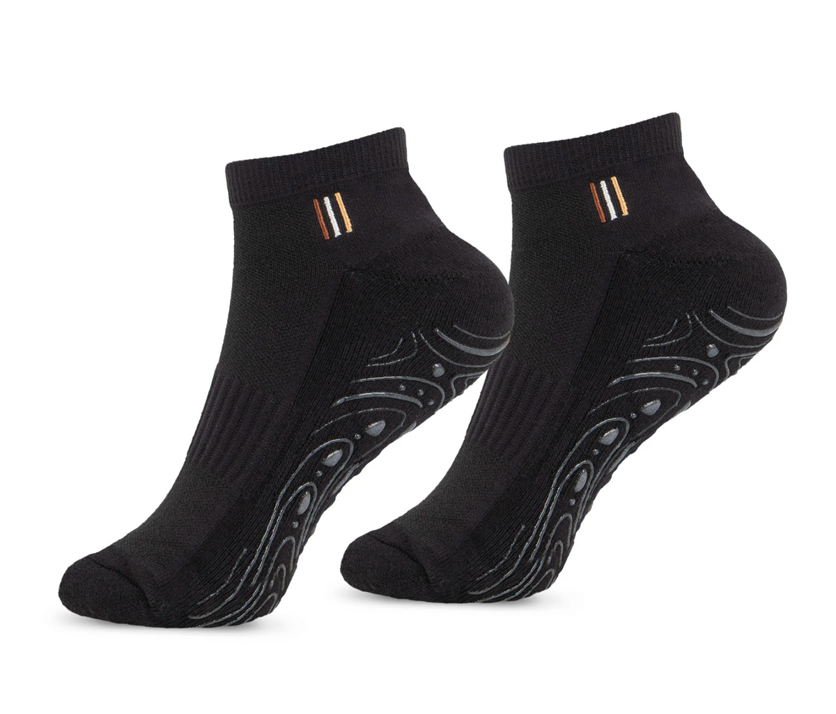 A pair of black low-cut ankle socks with a small gold, white, and black striped detail on the ribbed cuff, and a wavy gray grip pattern on the sole.